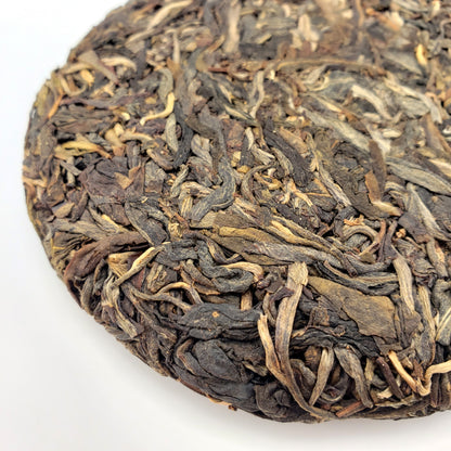 Close-up of a compressed tea cake with dried tea leaves on a white background