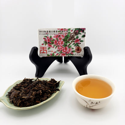 Tea packaging with floral design, a cup of tea, and a leaf of tea leaves on a white background.