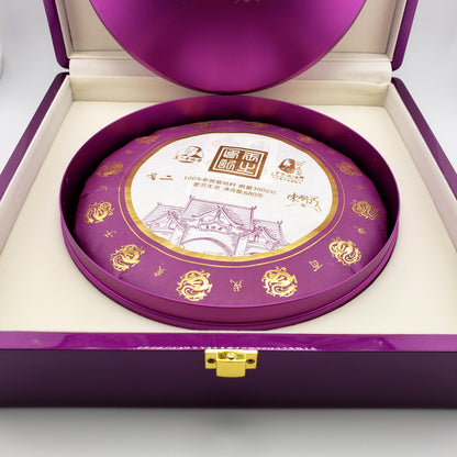 Round purple and white tea cake in a decorative purple box with gold accents
