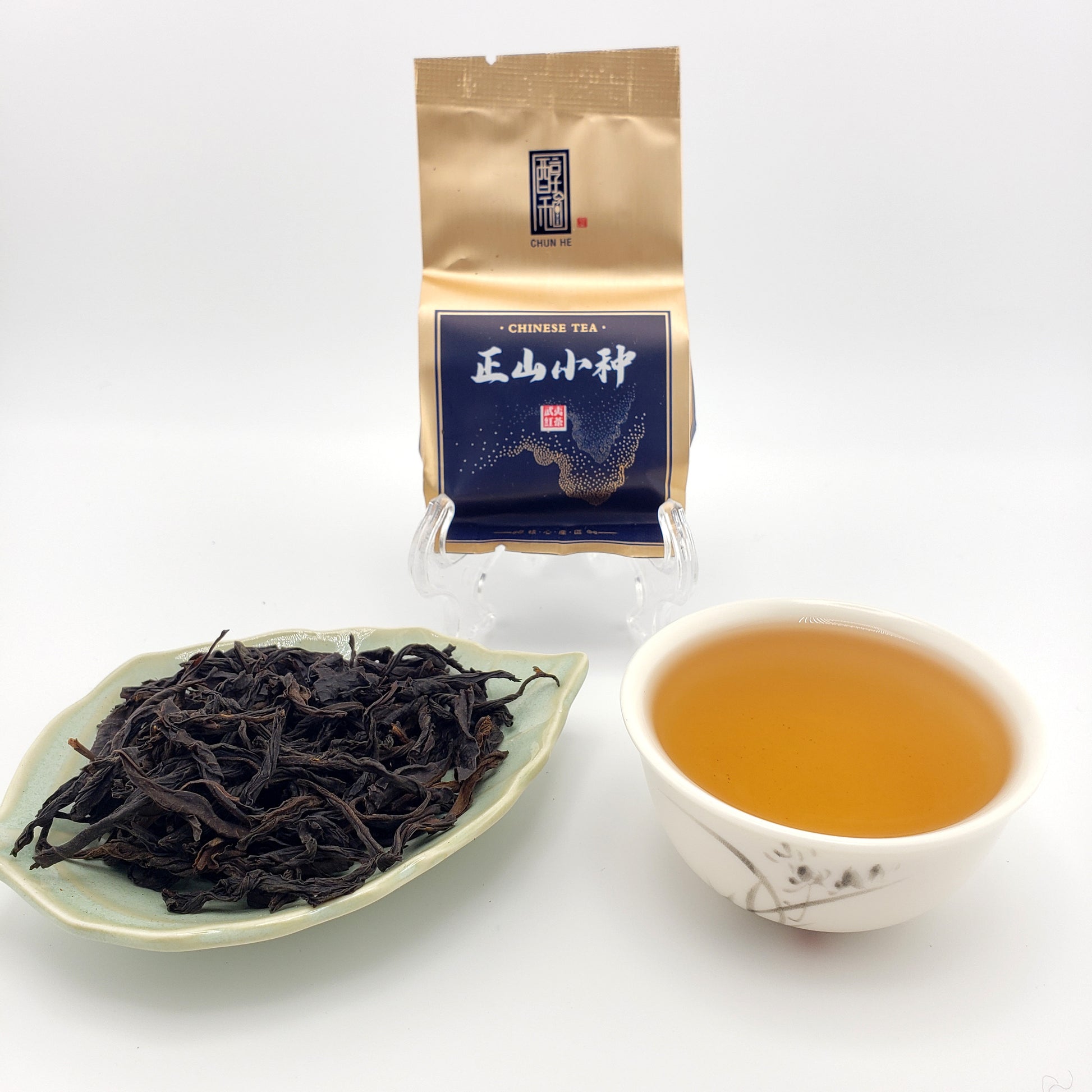 Tea packaging, brewed tea, and loose tea leaves on a white background
