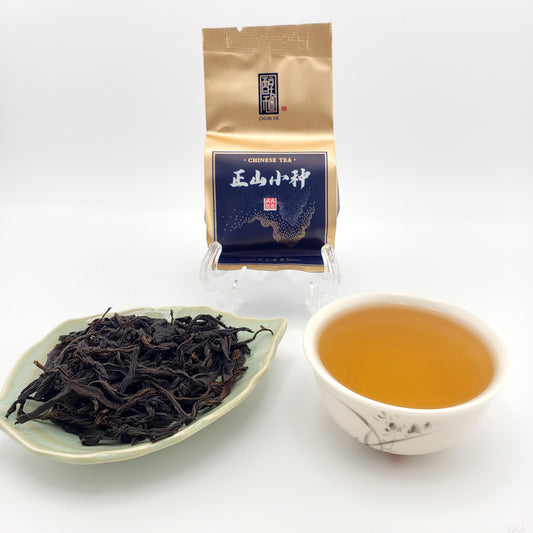 Tea packaging, brewed tea, and loose tea leaves on a white background