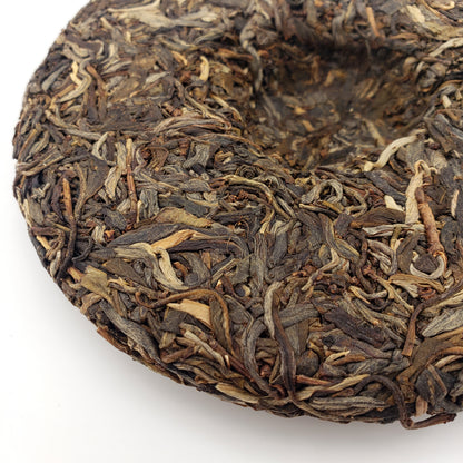 Close-up of a round cake of Pu-erh tea leaves on a white background