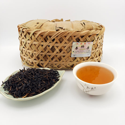 Woven basket of tea leaves with a cup of tea and a bowl of loose tea on a white background