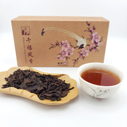 Beautifully decorated box behind a tray of tea leaves and a cup of brewed tea