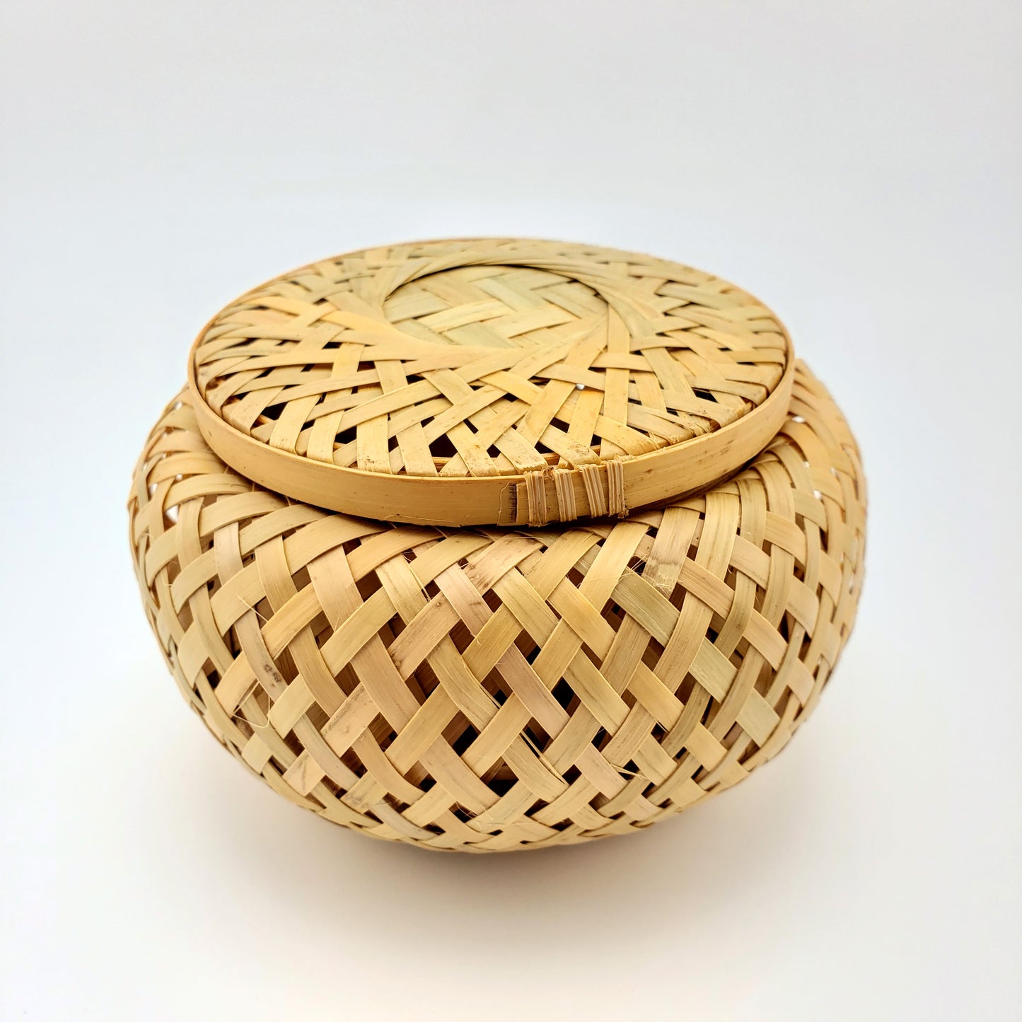 Woven bamboo basket with lid on a white background