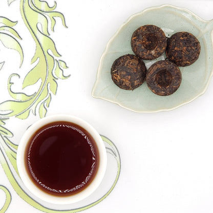 Tea balls on a plate with a cup of tea on a decorative mat