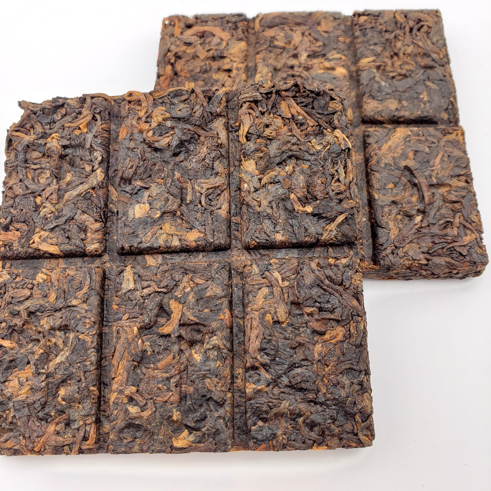 Square pieces of dark brown tea on a white background