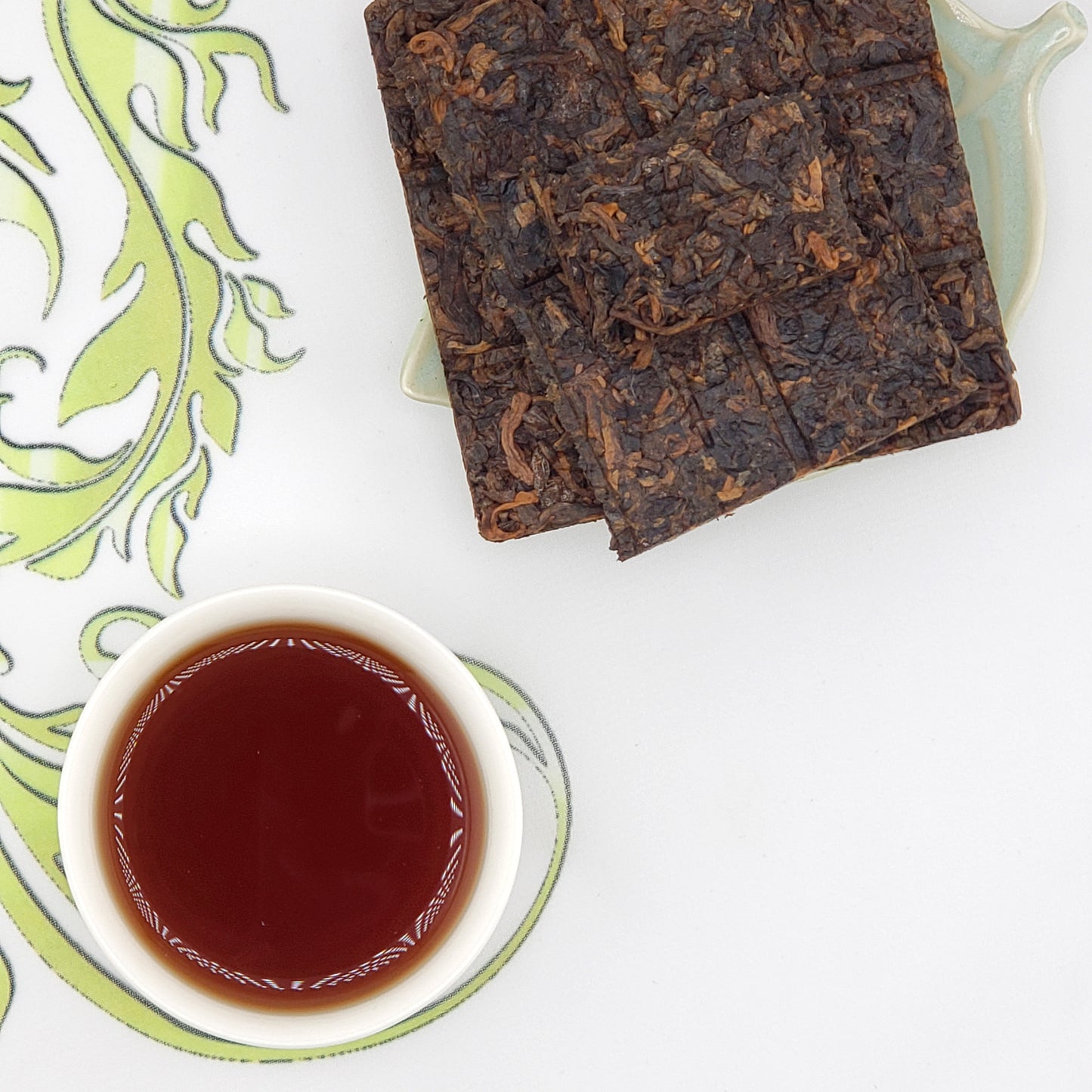 Tea leaves and a cup of tea on a decorative plate