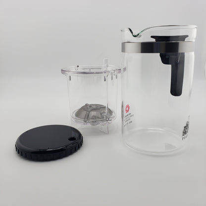 A clear glass teapot with a black lid and handle, shown with its clear infuser basket and black lid on a light gray background.