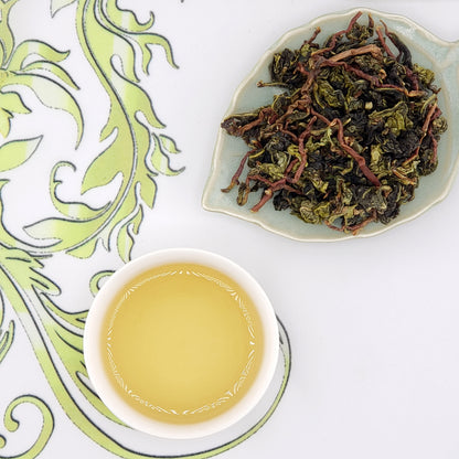 Tea cup with brewed tea and a dish of dry tea leaves on a decorative background