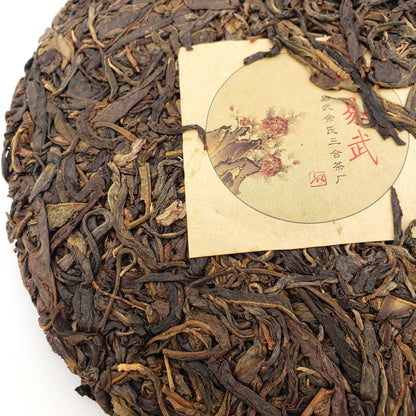 Close-up of a pressed tea cake with a label (nei fei) featuring floral design and text.
