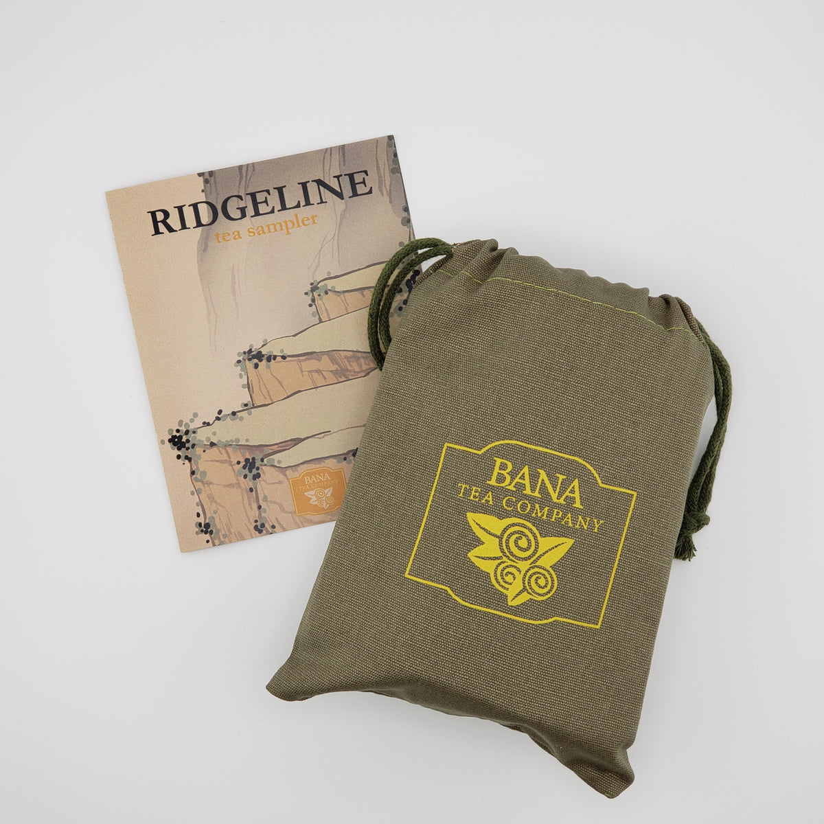 An olive green drawstring pouch with a yellow Bana Tea Company logo, shown next to a beige tea sample booklet labeled Ridgeline on a light gray background.