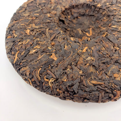 Close-up of a compressed tea cake with intricate patterns on a white background