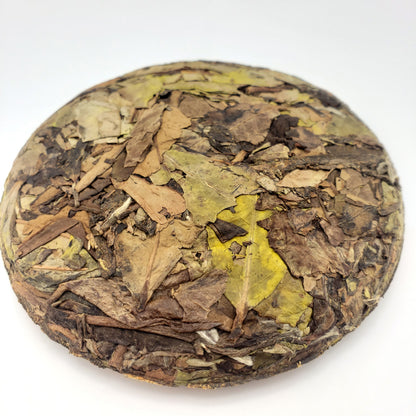 Round compressed tea ball with various colored tea leaves on a white background