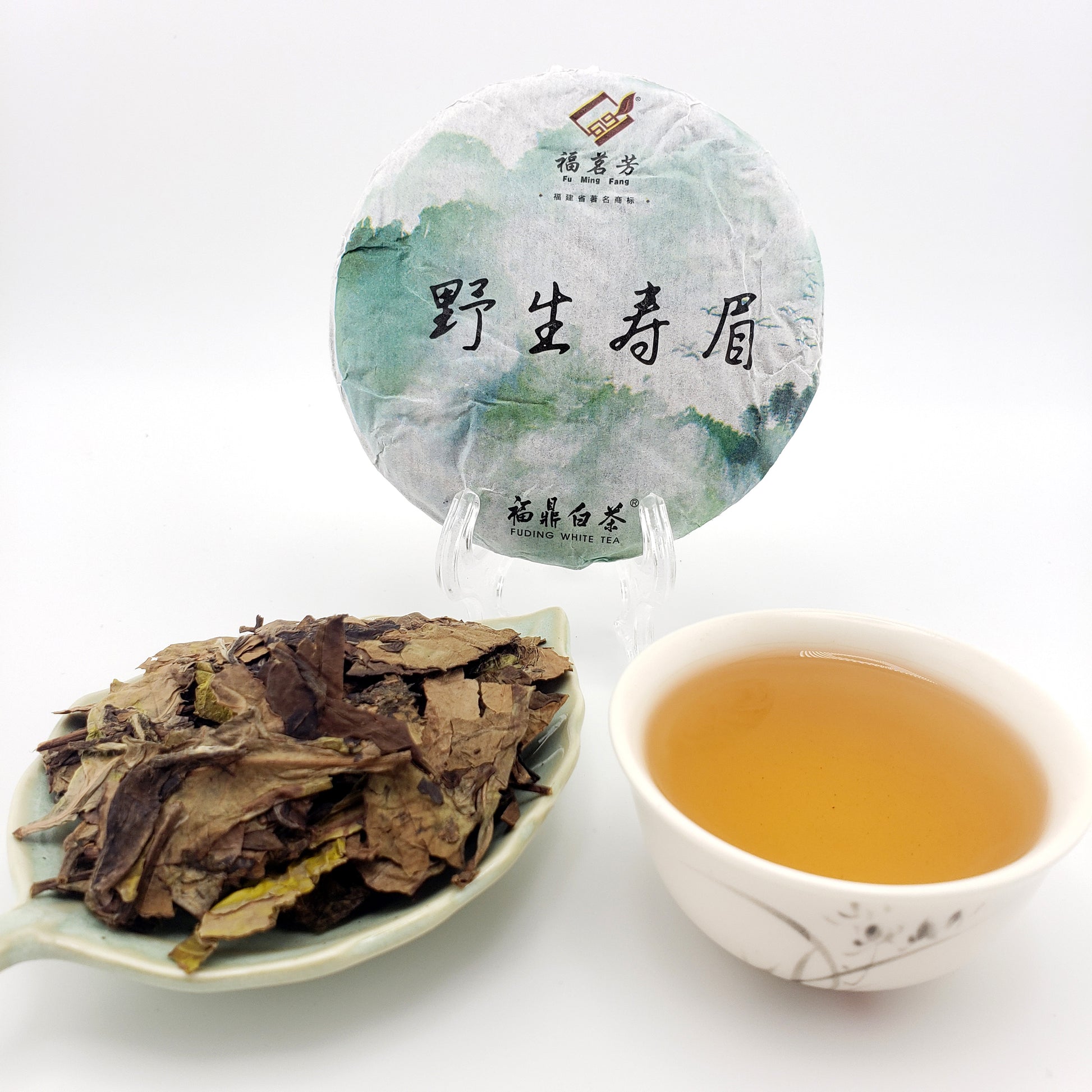 Tea cake, brewed tea in a cup, and loose tea leaves on a white background