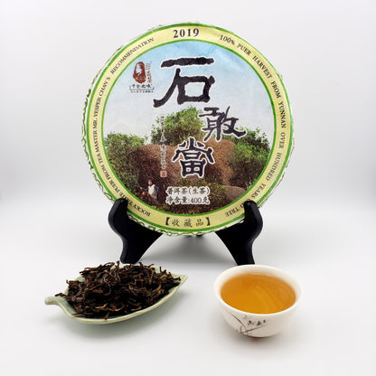 Tea packaging with a scoop of tea leaves and a cup of tea on a white background