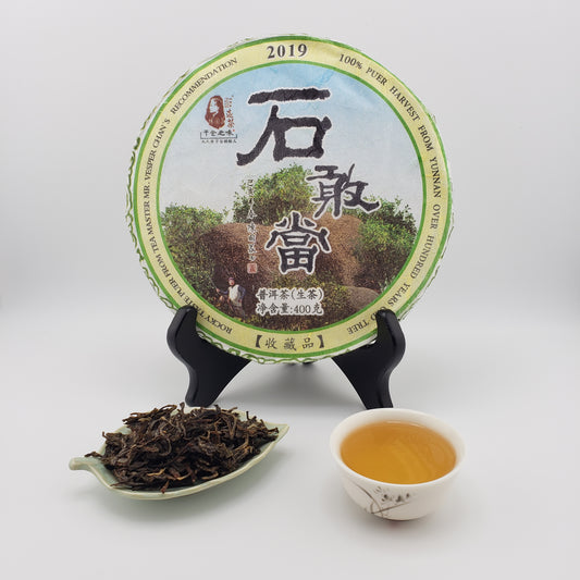 Tea packaging with a scoop of tea leaves and a cup of tea on a white background