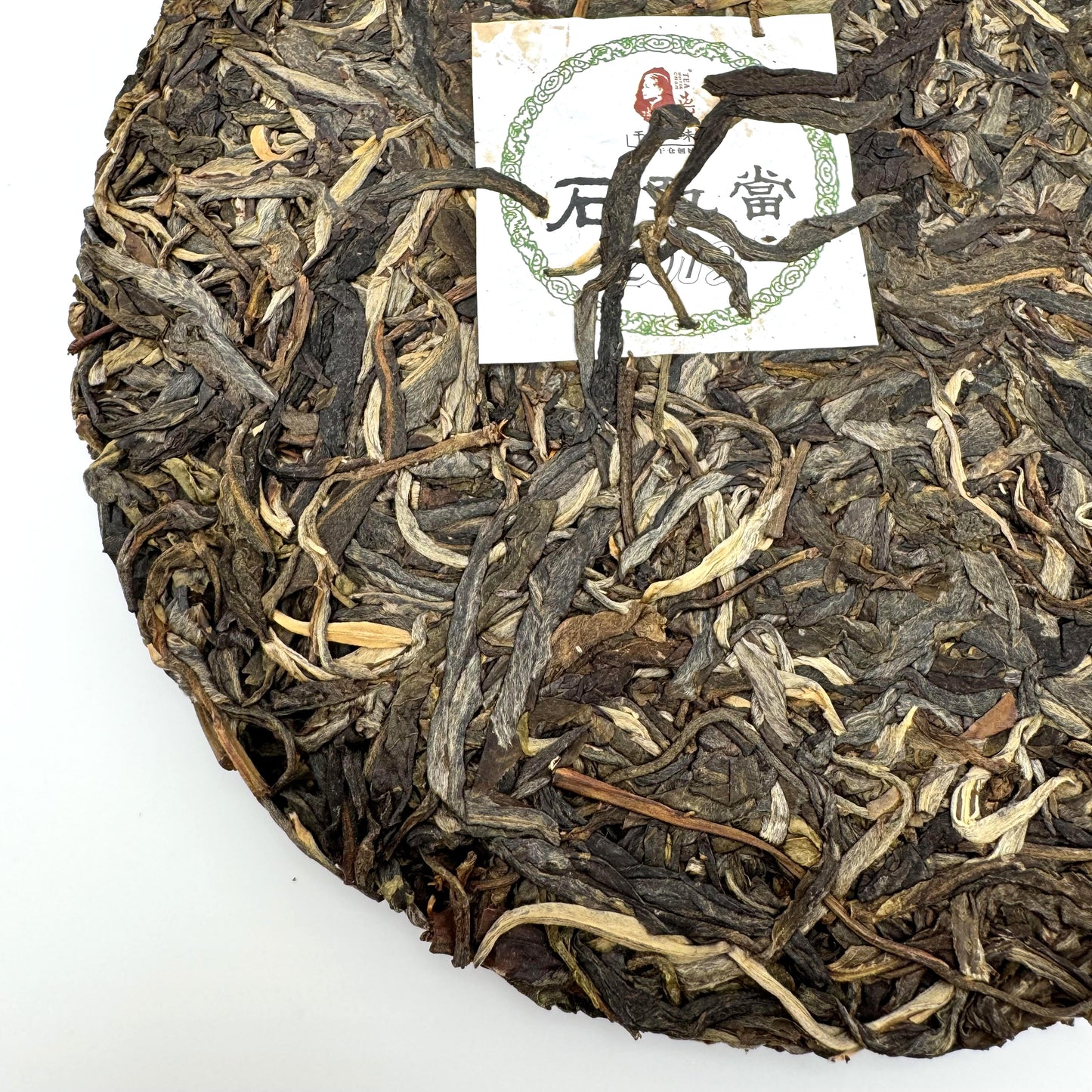 Round cake of pu-erh tea leaves with a nei fei label on a white background
