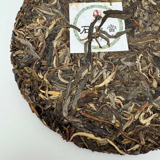 Round cake of pu-erh tea leaves with a nei fei label on a white background