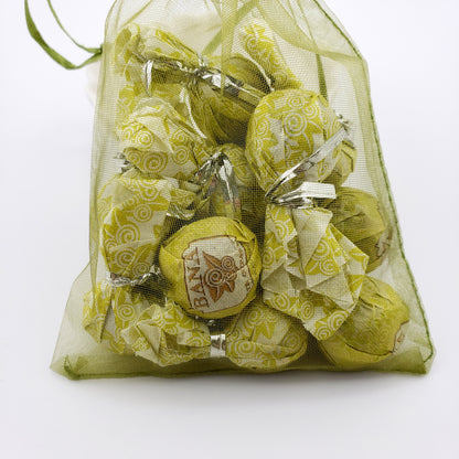 Green mesh bag filled with wrapped tea balls on a white background