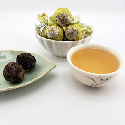 Tea balls and a cup of tea on a white surface