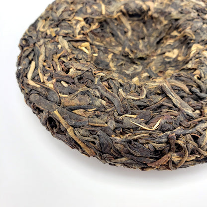 Close-up of a compressed tea cake with intricate leaf patterns on a white background