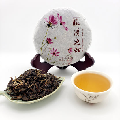 Tea packaging with a spoonful of tea leaves and a cup of tea on a white background