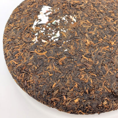 Close-up of a tea cake with visible tea leaves on a white background