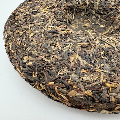 Close-up of a round cake of pressed tea leaves on a white background