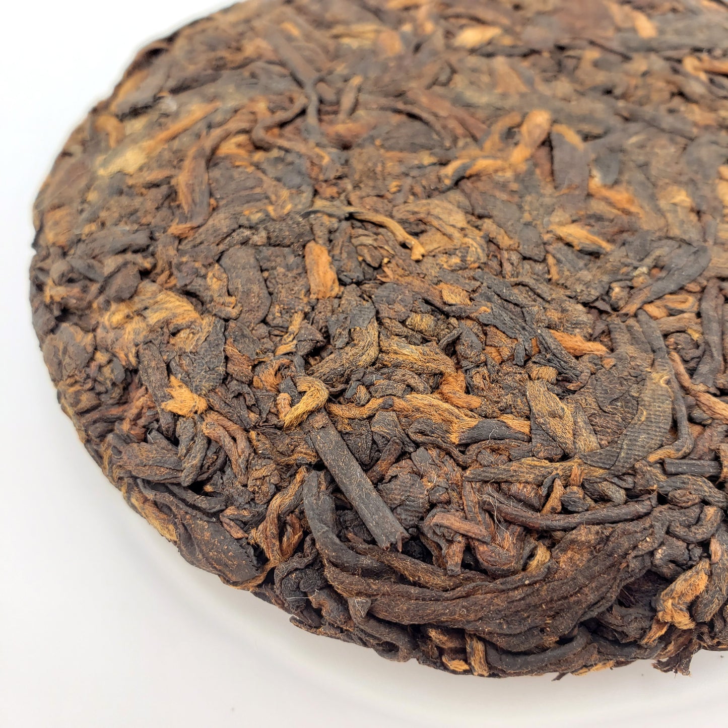 Close-up of a compressed tea ball with intricate texture on a white background