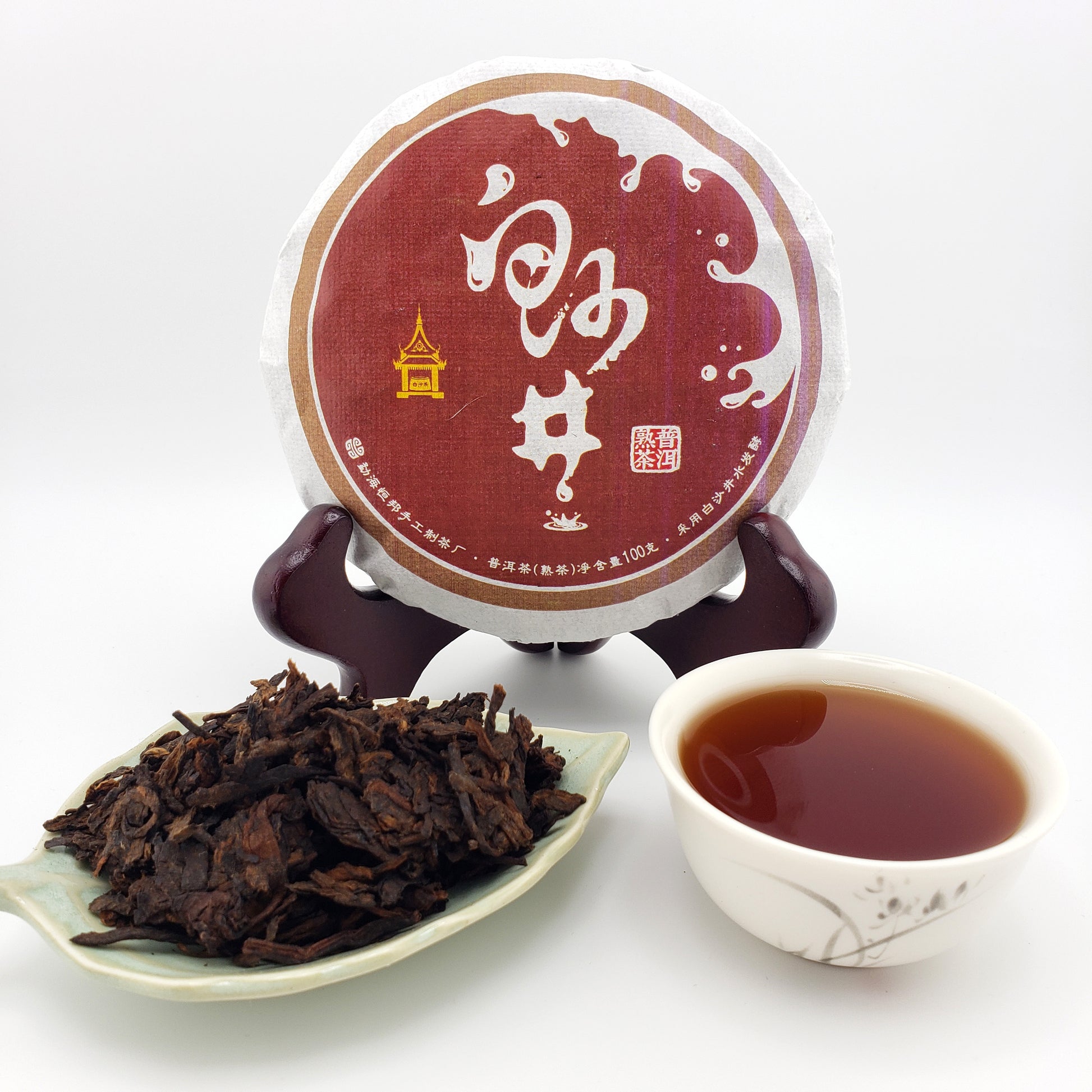 Puer tea cake with a cup of tea and tea leaves on a white background