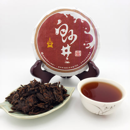 Puer tea cake with a cup of tea and tea leaves on a white background