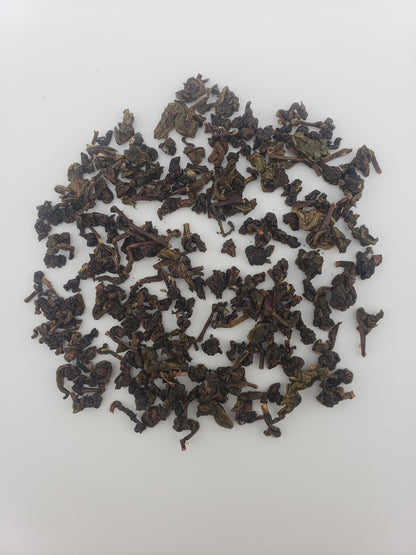 A pile of dark, tightly rolled loose-leaf tea on a plain white background.