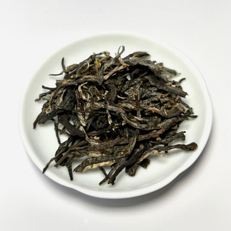 Dried tea leaves on a white plate with a white background