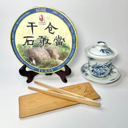 Tea packaging with a teapot, chopsticks, and wooden tray on a white background