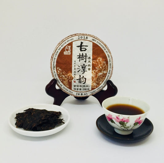 Pu-erh tea cake with a cup of tea and tea leaves on a white background