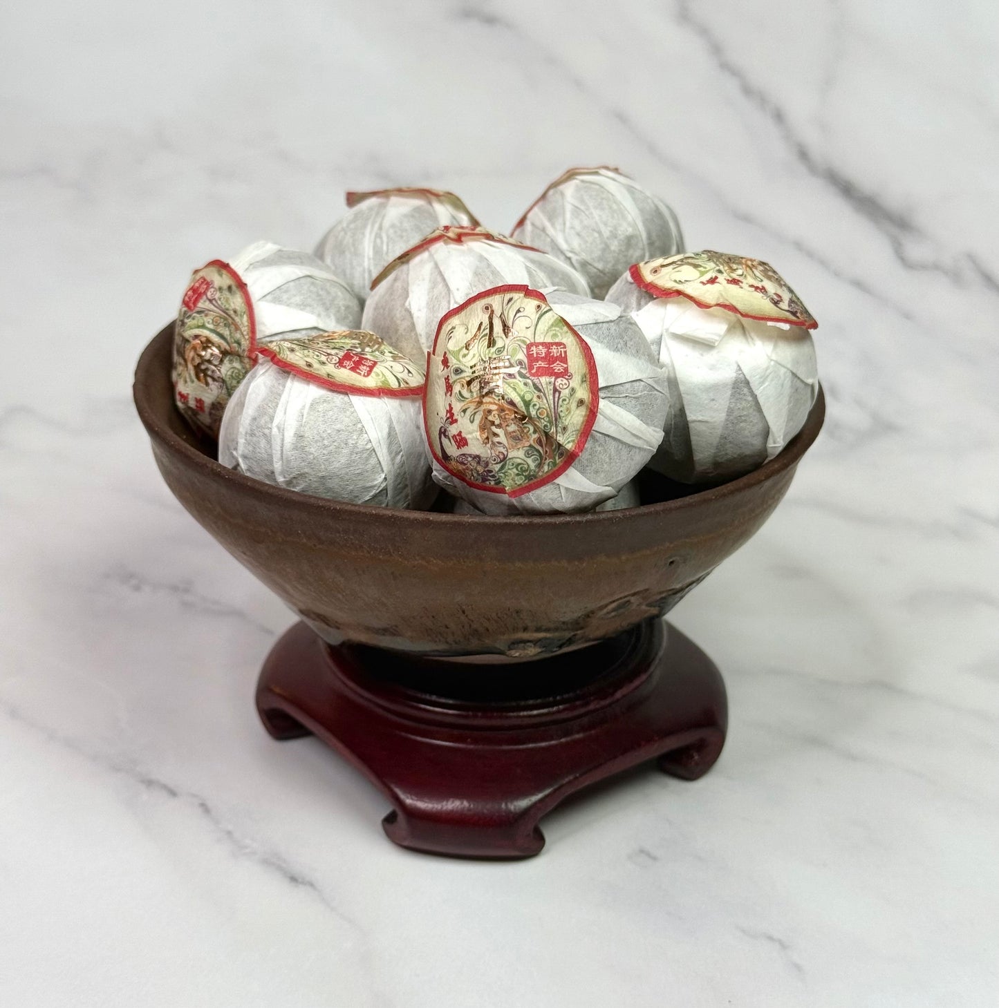 Tea balls in a wooden bowl on a marble surface