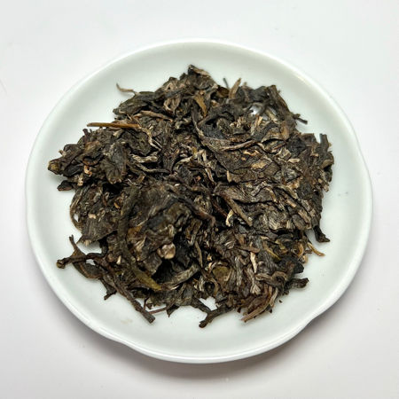 Dry tea leaves on a white plate with a white background