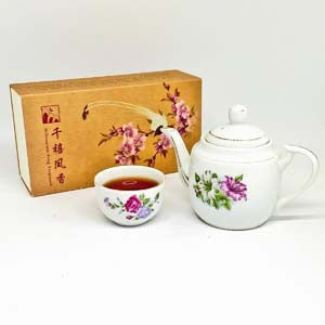 Tea set with floral design including a teapot, cup, and tea box on a white background