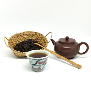 Tea set with a teapot, cup, and woven basket on a white background