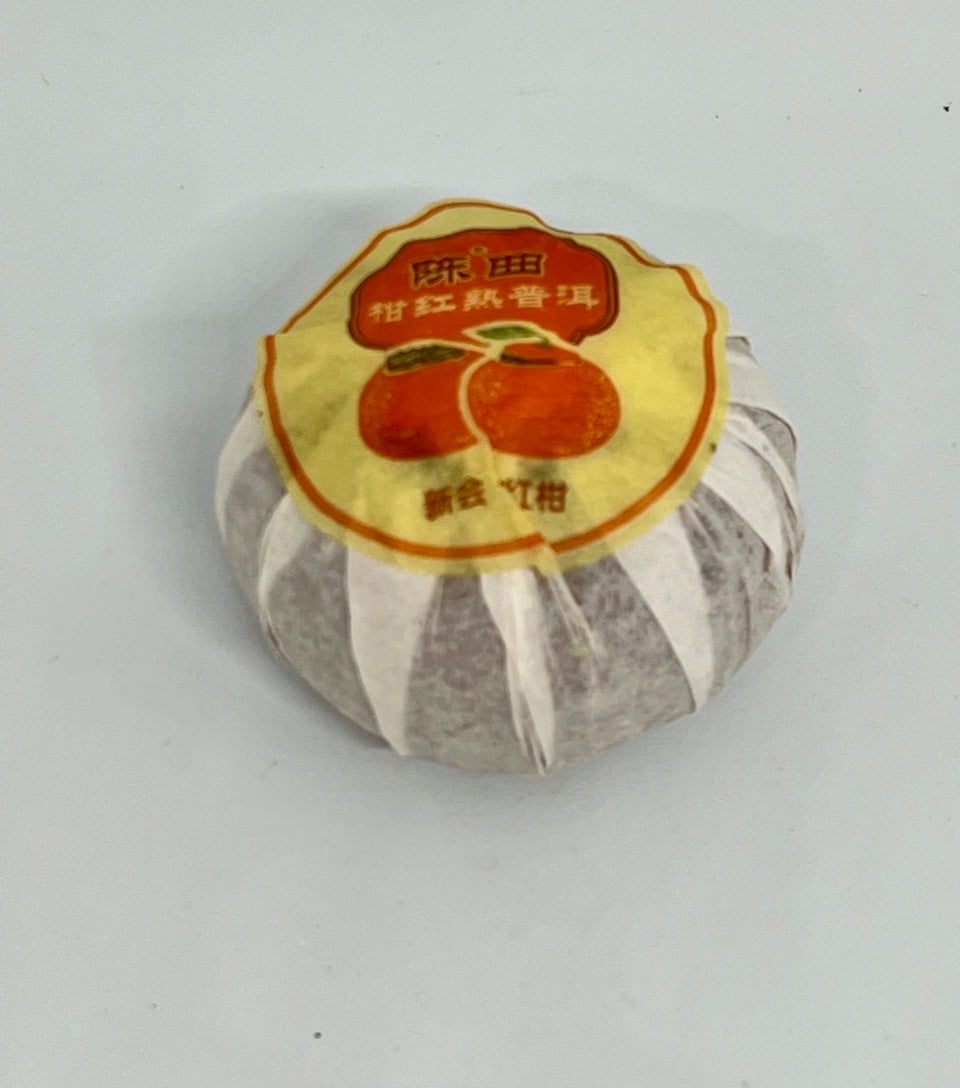 Tea package with a yellow label featuring an orange on a light gray background