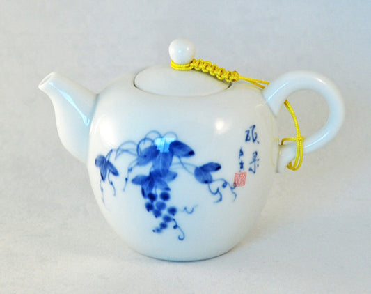 White teapot with blue floral design on a light gray background